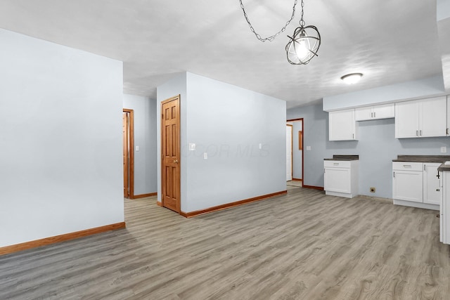 kitchen with pendant lighting, white cabinetry, and light hardwood / wood-style flooring