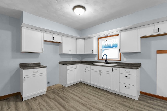 kitchen featuring sink, light hardwood / wood-style flooring, and white cabinets