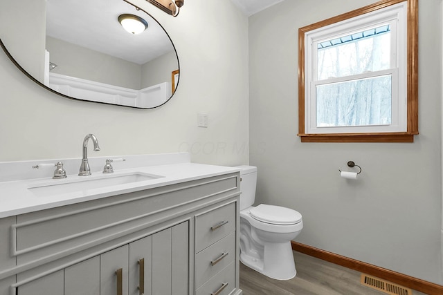 bathroom with hardwood / wood-style flooring, vanity, and toilet