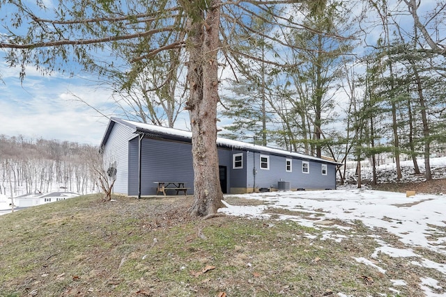 snow covered rear of property featuring central AC unit