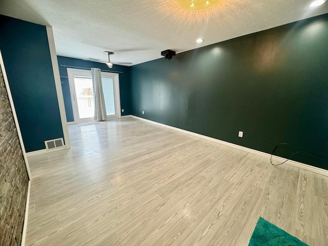 spare room featuring a textured ceiling and light hardwood / wood-style flooring