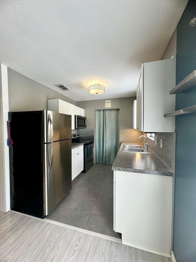 kitchen with decorative backsplash, sink, white cabinets, and appliances with stainless steel finishes