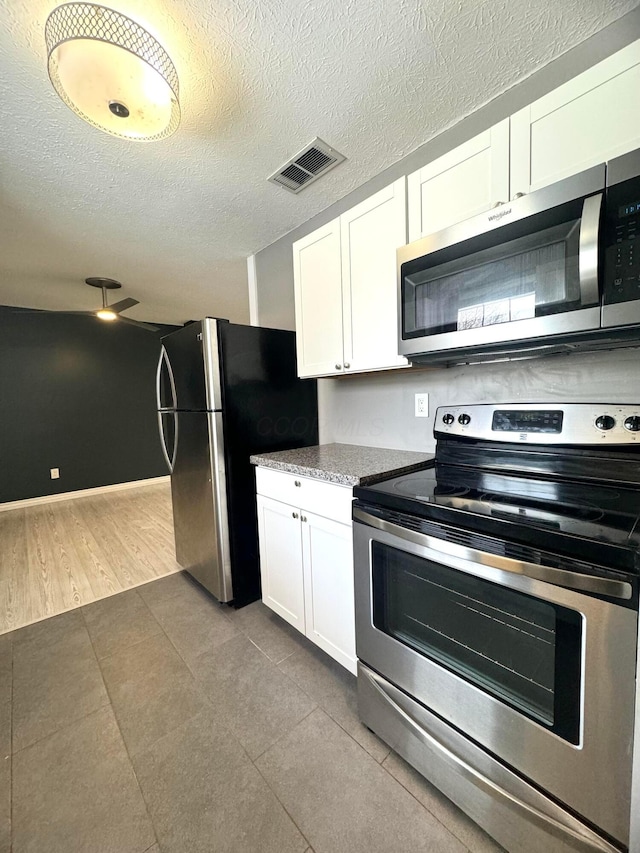 kitchen featuring appliances with stainless steel finishes, white cabinets, visible vents, and a textured ceiling