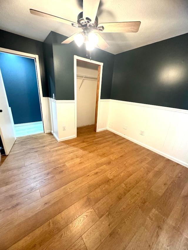 unfurnished bedroom with ceiling fan, a closet, a textured ceiling, and light hardwood / wood-style floors