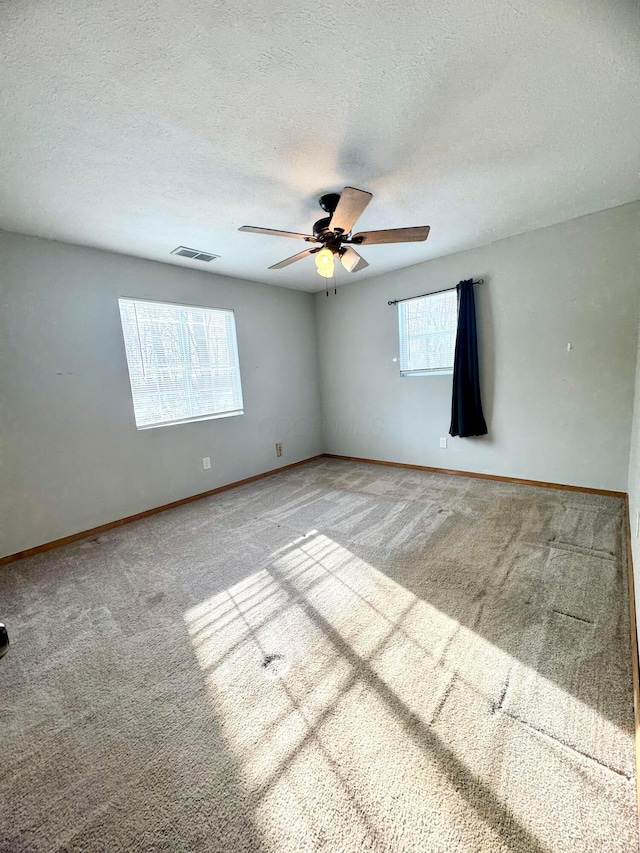 carpeted empty room with ceiling fan and a textured ceiling