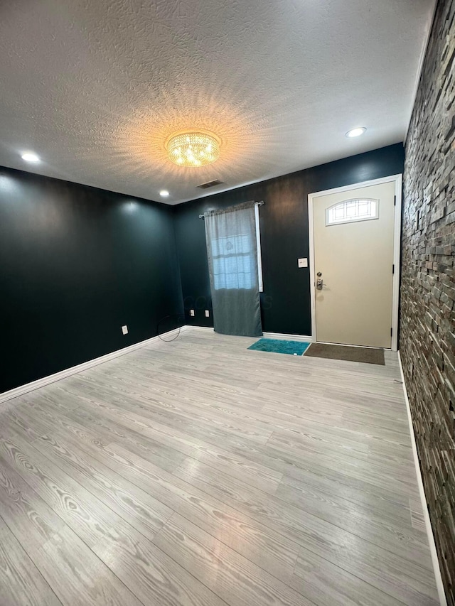 foyer with a textured ceiling and light hardwood / wood-style flooring