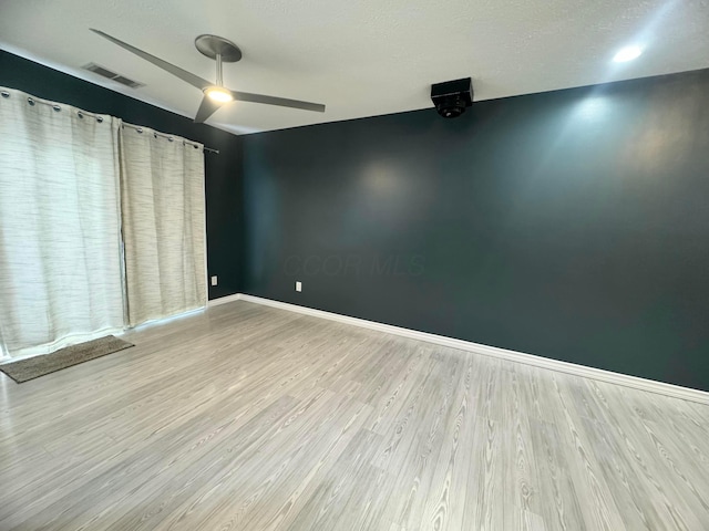 empty room featuring baseboards, visible vents, ceiling fan, and wood finished floors