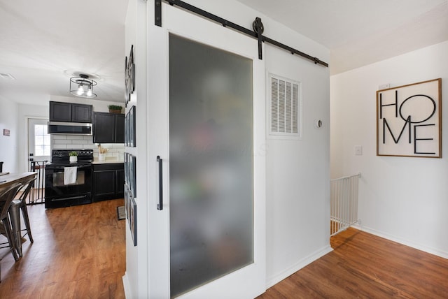 kitchen with range hood, tasteful backsplash, black electric range, dark hardwood / wood-style flooring, and a barn door