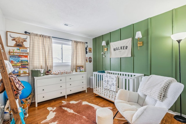 bedroom with hardwood / wood-style flooring and a crib