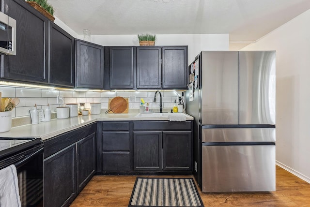 kitchen featuring stainless steel appliances, sink, hardwood / wood-style floors, and backsplash