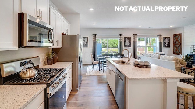 kitchen with appliances with stainless steel finishes, sink, an island with sink, and white cabinets