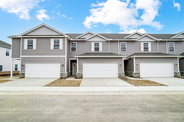 multi unit property with concrete driveway, a garage, stone siding, and a shingled roof