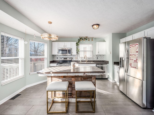 kitchen with decorative light fixtures, white cabinets, and appliances with stainless steel finishes