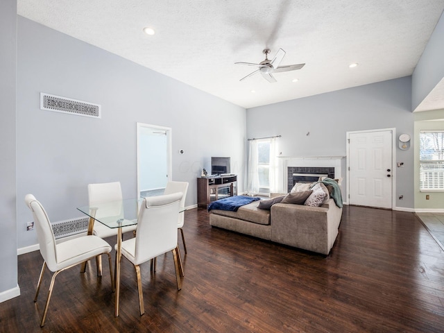 dining area featuring ceiling fan, a textured ceiling, dark hardwood / wood-style flooring, and a fireplace