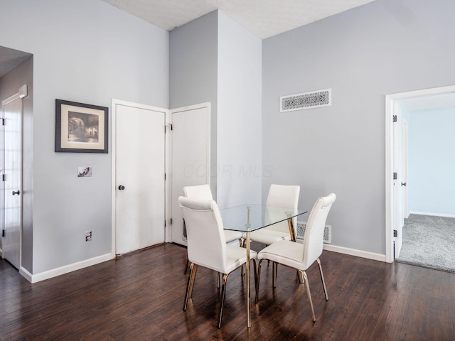 dining room featuring dark hardwood / wood-style floors, a towering ceiling, and a textured ceiling