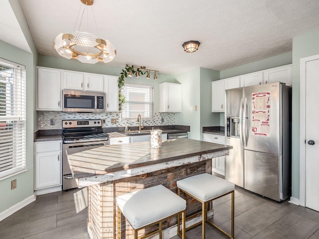 kitchen with decorative backsplash, white cabinetry, stainless steel appliances, and pendant lighting