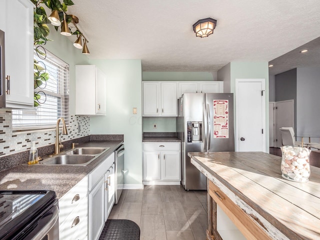 kitchen featuring a textured ceiling, sink, stainless steel appliances, and white cabinetry