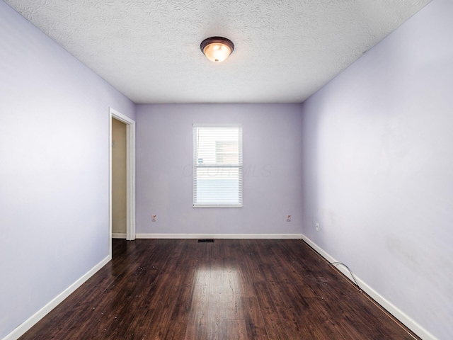 unfurnished room with a textured ceiling and dark wood-type flooring