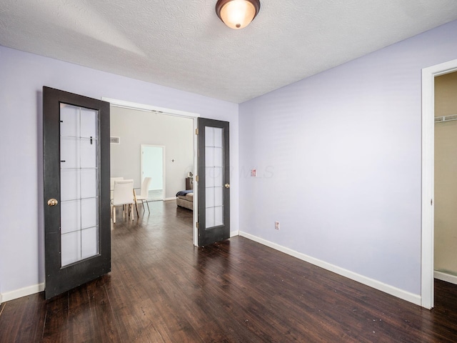 spare room featuring a textured ceiling, dark hardwood / wood-style flooring, and french doors