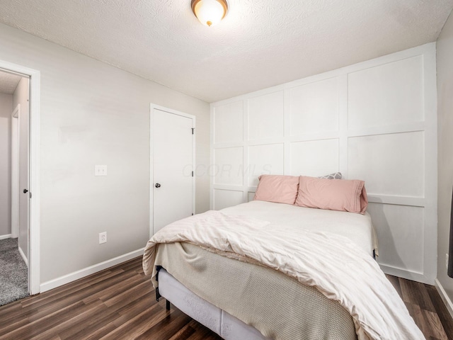 bedroom featuring a textured ceiling and dark hardwood / wood-style floors