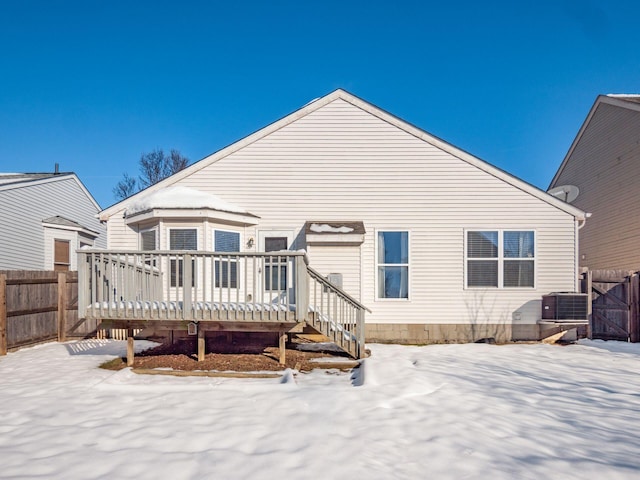 snow covered back of property featuring cooling unit and a wooden deck