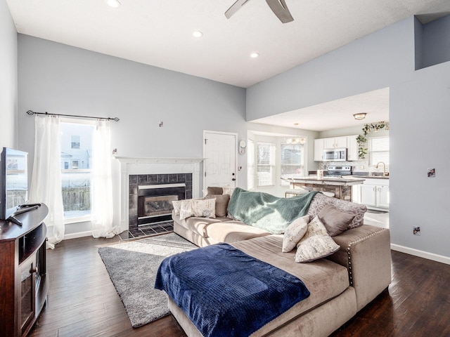 living room featuring ceiling fan, dark wood-type flooring, sink, and a fireplace