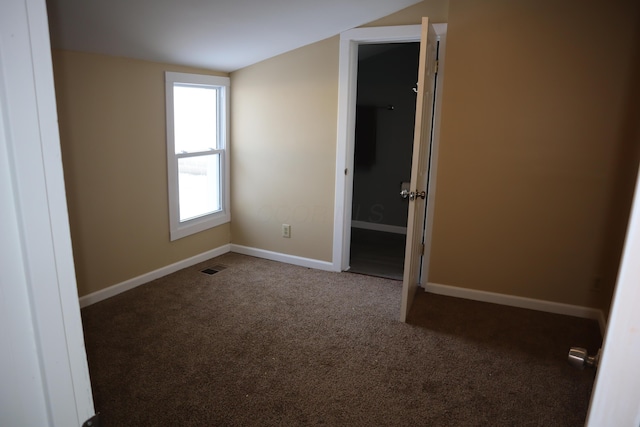 spare room with lofted ceiling and dark carpet