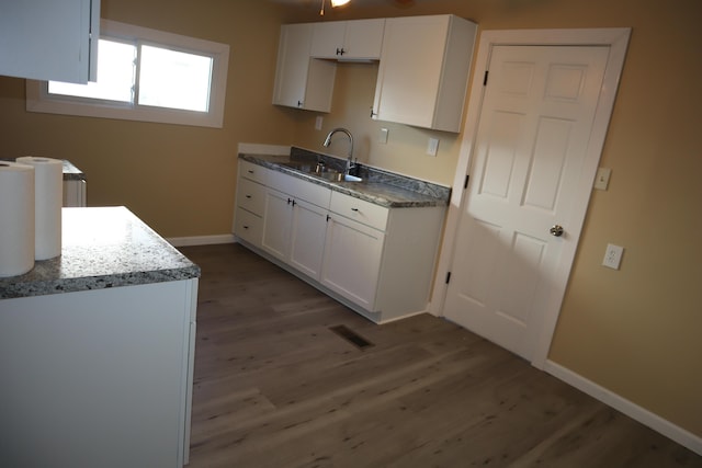 kitchen featuring dark stone countertops, wood-type flooring, sink, and white cabinets