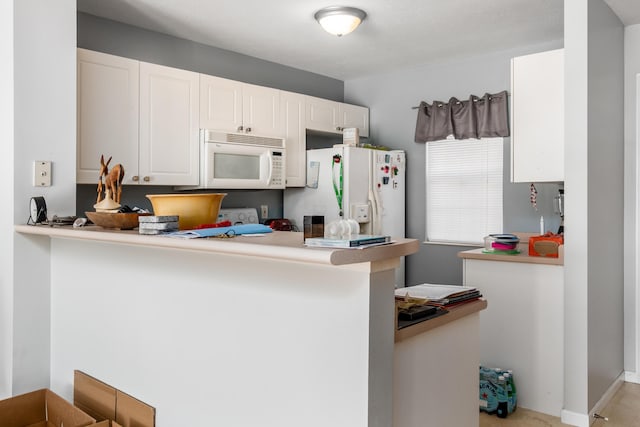 kitchen with white cabinets, white appliances, and kitchen peninsula