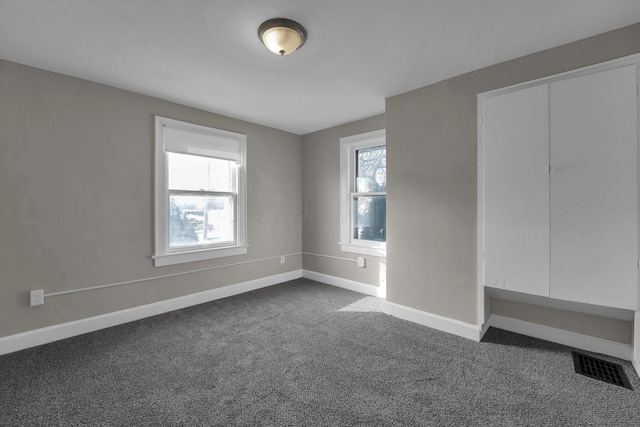 unfurnished bedroom with a closet and dark carpet