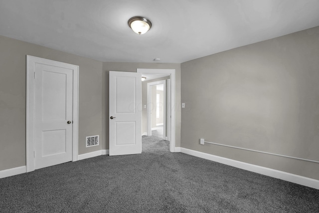 unfurnished room featuring dark colored carpet