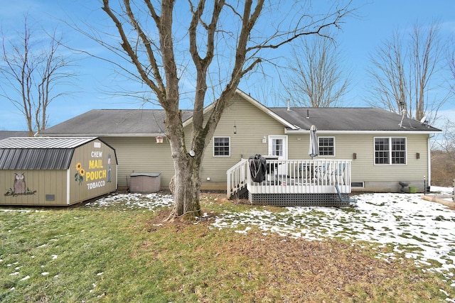 snow covered property with a wooden deck, a lawn, and a shed