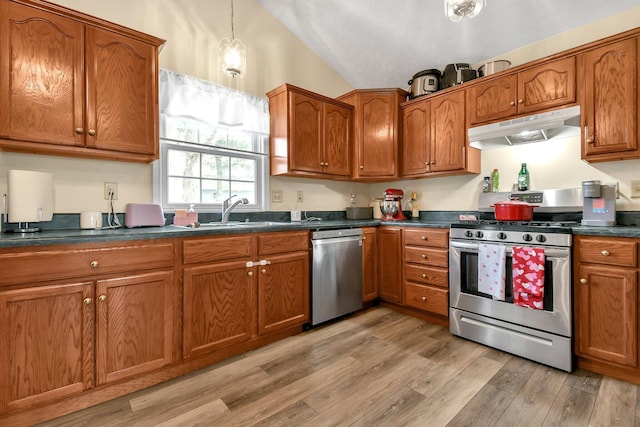 kitchen with pendant lighting, lofted ceiling, sink, stainless steel appliances, and light hardwood / wood-style flooring