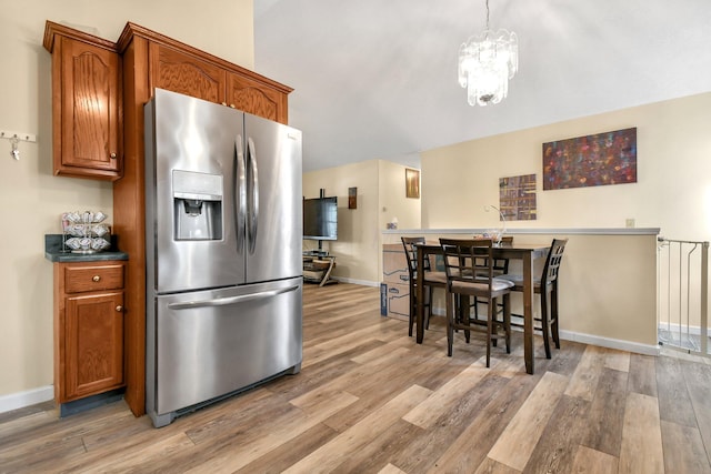 kitchen featuring stainless steel fridge, light hardwood / wood-style flooring, and a notable chandelier