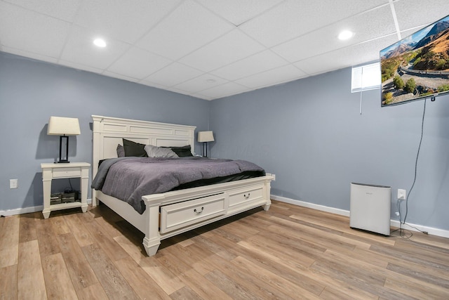 bedroom featuring a drop ceiling and light hardwood / wood-style flooring