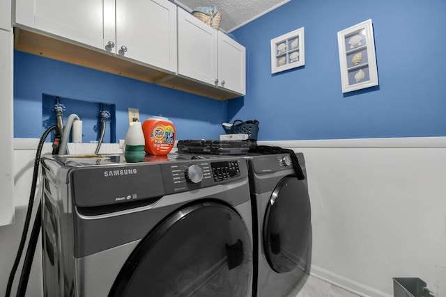 washroom featuring washer and clothes dryer, cabinets, and a textured ceiling