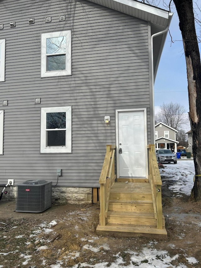 snow covered rear of property featuring cooling unit