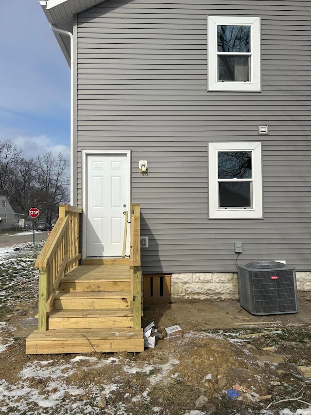 snow covered property entrance featuring cooling unit