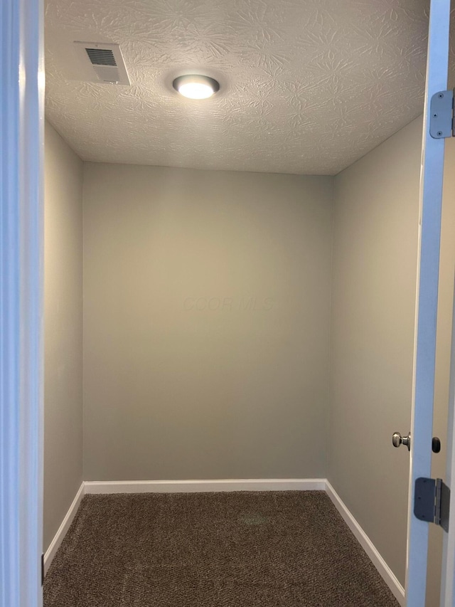 carpeted empty room featuring a textured ceiling