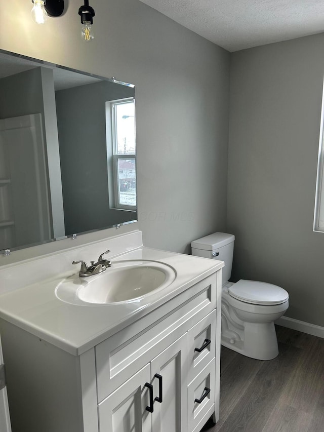 bathroom featuring a textured ceiling, toilet, hardwood / wood-style floors, and vanity