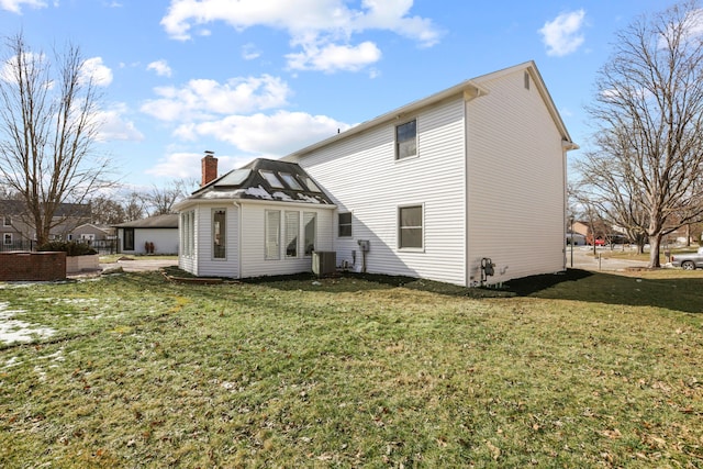 rear view of property featuring central AC unit and a yard