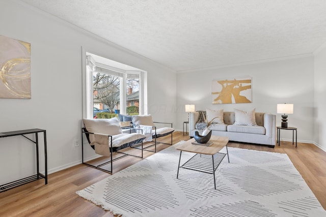 living room featuring ornamental molding, a textured ceiling, and light hardwood / wood-style flooring