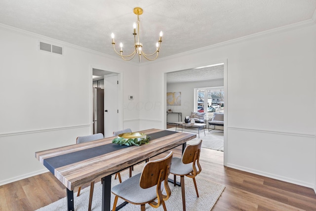 dining area featuring an inviting chandelier, wood-type flooring, and a textured ceiling