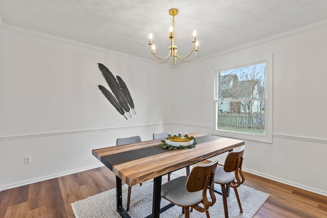 dining room featuring wood-type flooring, ornamental molding, an inviting chandelier, and a textured ceiling