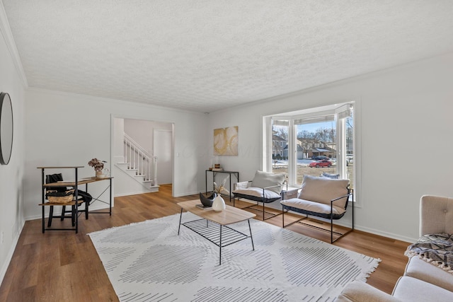 living room with wood-type flooring, crown molding, and a textured ceiling