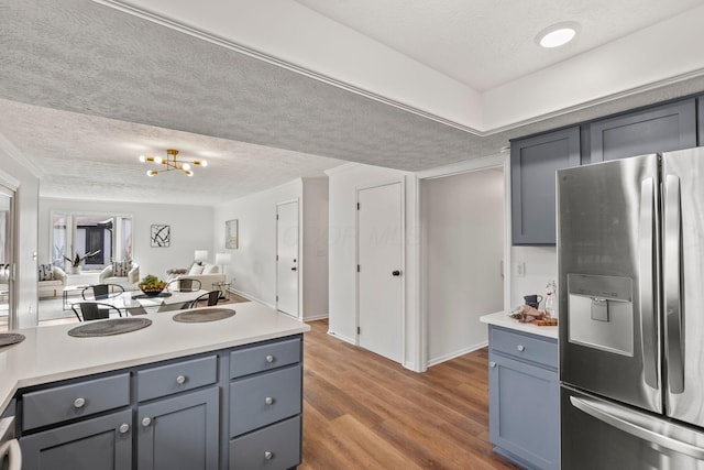 kitchen with ornamental molding, dark wood-type flooring, stainless steel fridge, and a textured ceiling