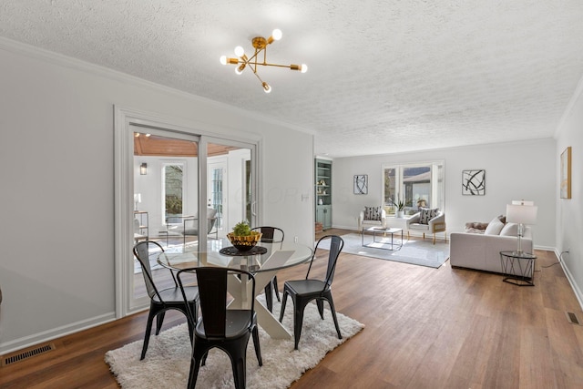 dining space featuring a notable chandelier, crown molding, dark wood-type flooring, and a textured ceiling