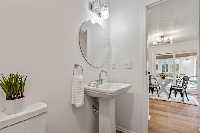 bathroom featuring toilet, sink, wood-type flooring, a textured ceiling, and ornamental molding