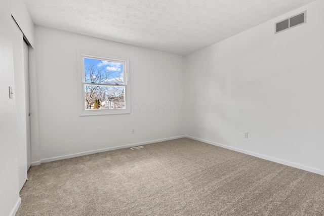 carpeted empty room with a textured ceiling