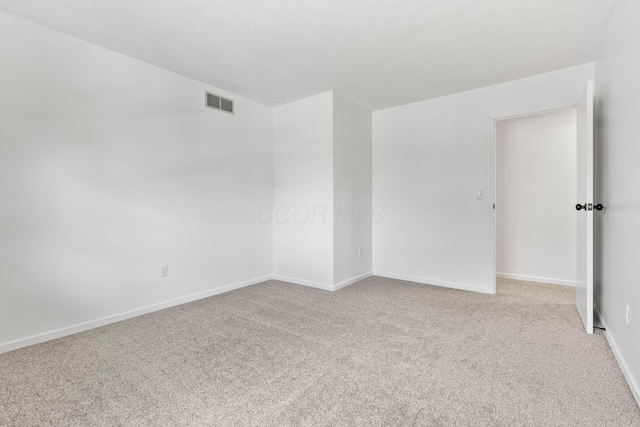 carpeted empty room featuring a textured ceiling